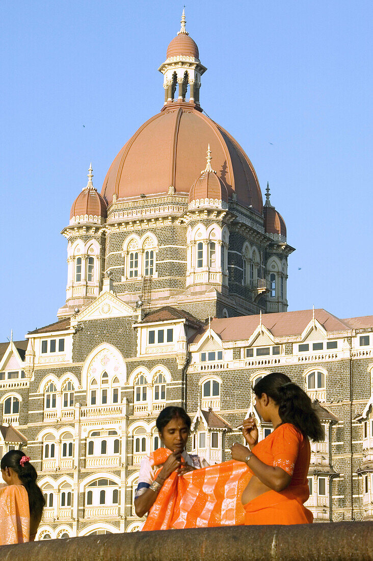 Women getting dressed in saris in front of the Taj Mahal Palace & Tower. Mumbai (ex Bombay). India