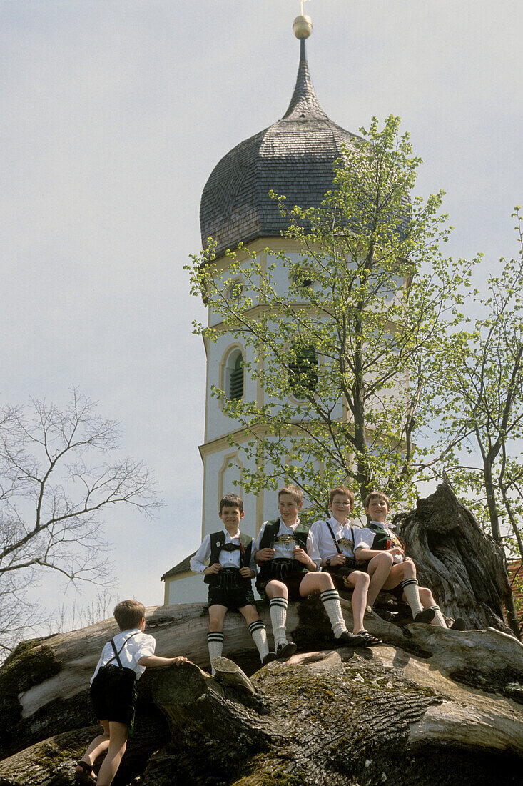 Five boys wearing lederhosen sitting outside a church, Holzhausen, Lake Starnberg, Upper Bavaria, Bavaria, Germany