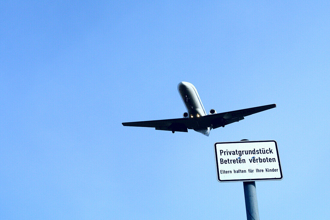 Airplane against blue sky, keep off sign in foreground, Berlin, Germany