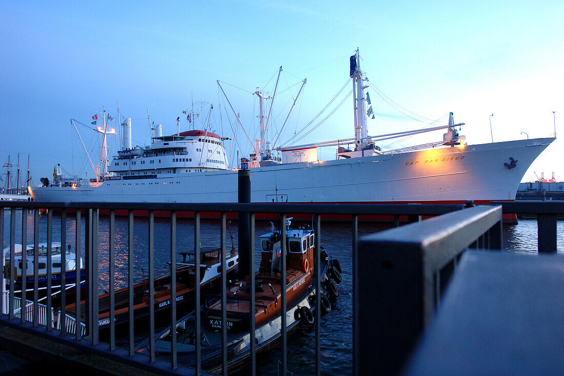 Frachtschiff und Schlepper am Abend im Hafen, Hamburg, Deutschland