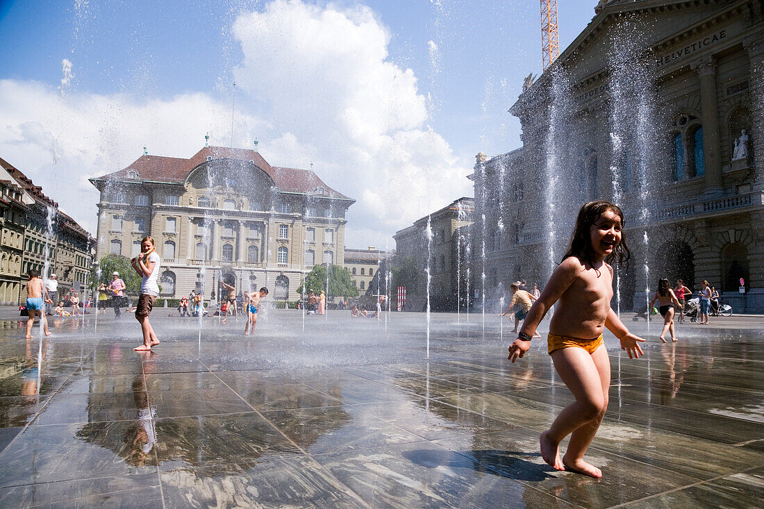 Children playing in the trick fountains and water gardens in front of the House of Parliament on Parliament Square, Bundeshaus, Bundesplatz, Old City of Berne, Berne, Switzerland