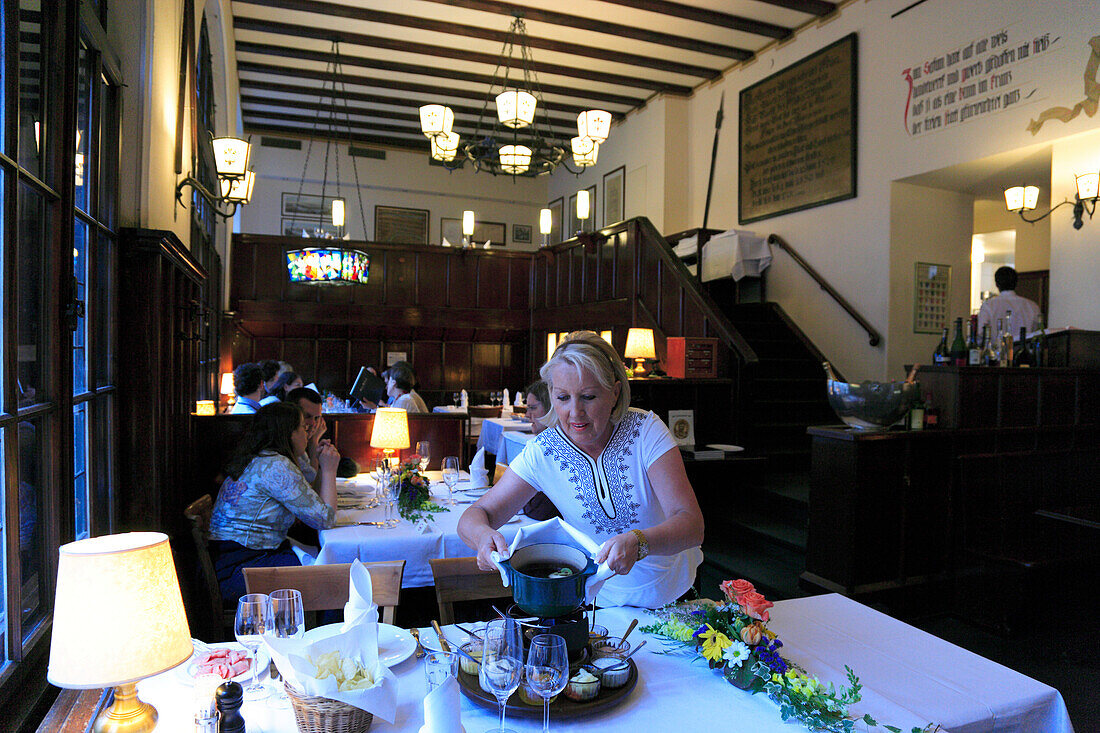 Waitress serving a fondue in Restaurant Safranzunft, Fondue Bacchus, Basel, Switzerland