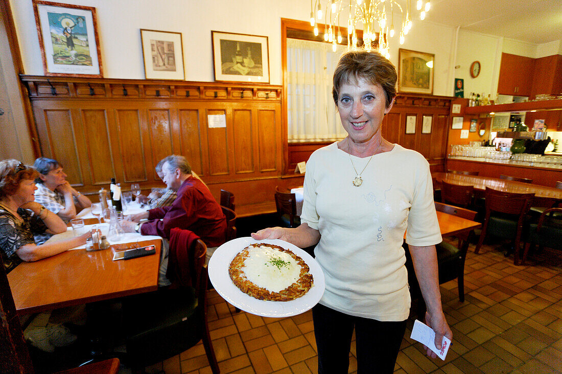 A waitress carrying traditional food, Roesti, in Restaurant Hasenburg, Basel, Switzerland