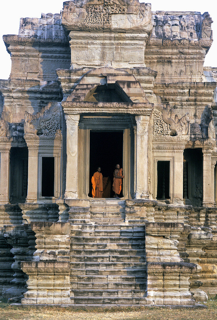 Monks at the southwest entrance of the gallery surrounding the Angkor Wat temple, temple complex of Angkor. Siem Riep, Cambodia