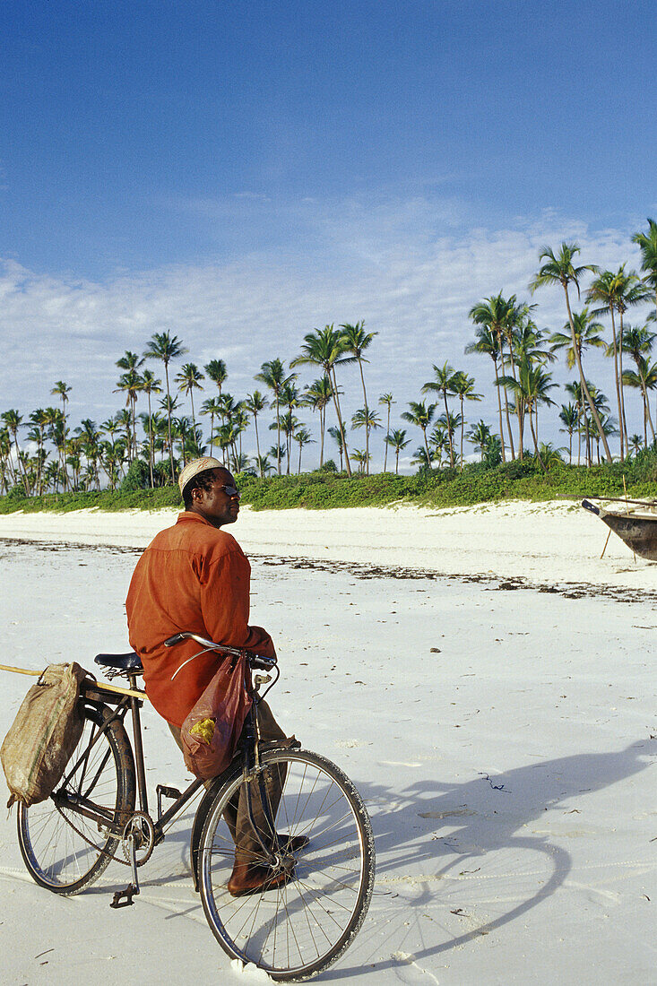 African man leaning on his bicycle at the white sandy beach of the east of Unguja Island, Zanzibar Archipelago, Tanzania, East Africa