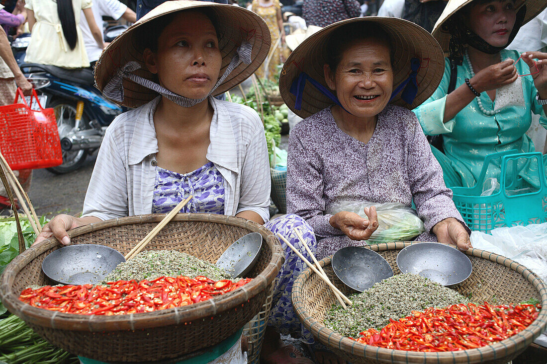 Two women sitting on the floor and selling freshly cut chilly on the fresh food market of Hoi An, Vietnam, Southeast Asia