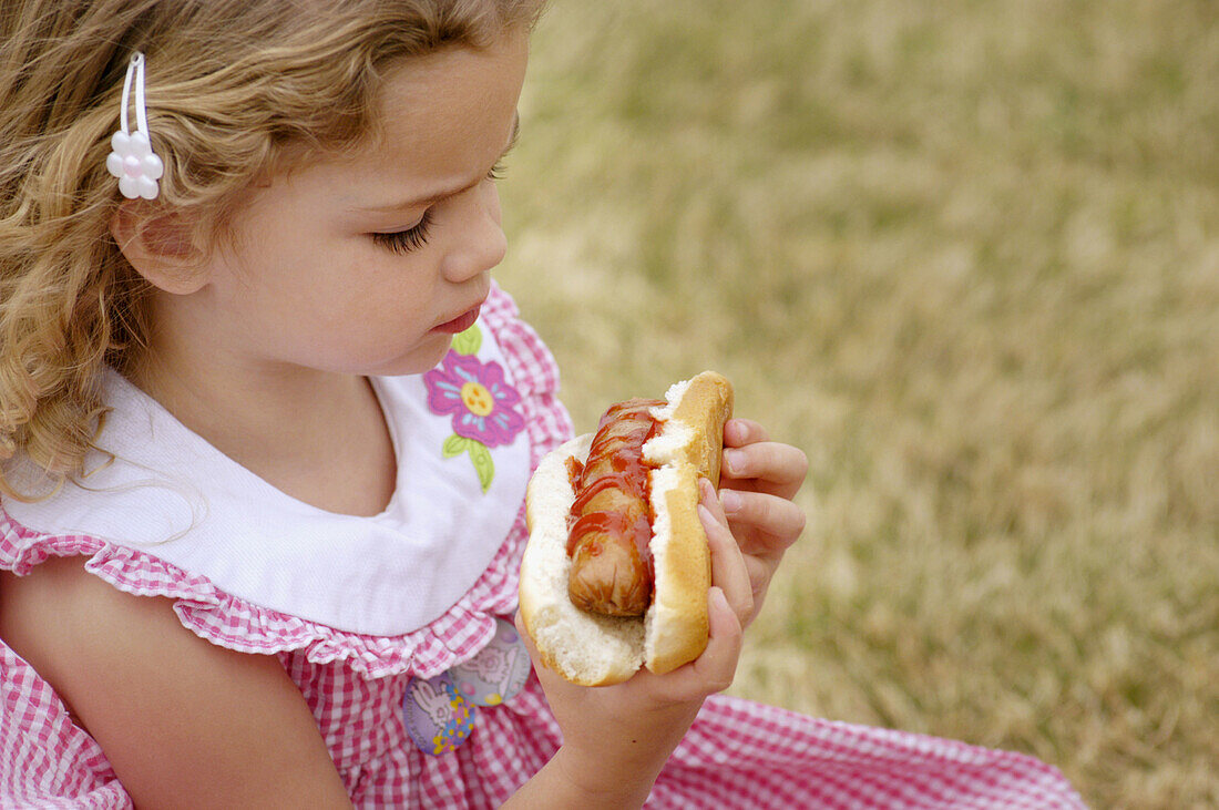 4 year old eating hot dog at event in private club park.
