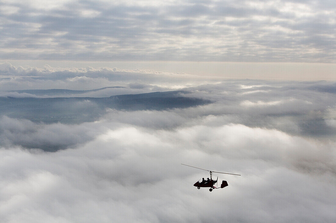 Autogyro flying over clouds, Lower Saxony, Germany