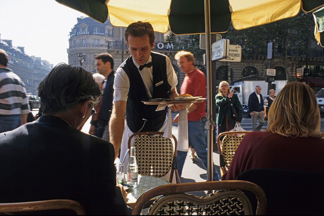 Waiter serving coffee at a Café in Paris, France