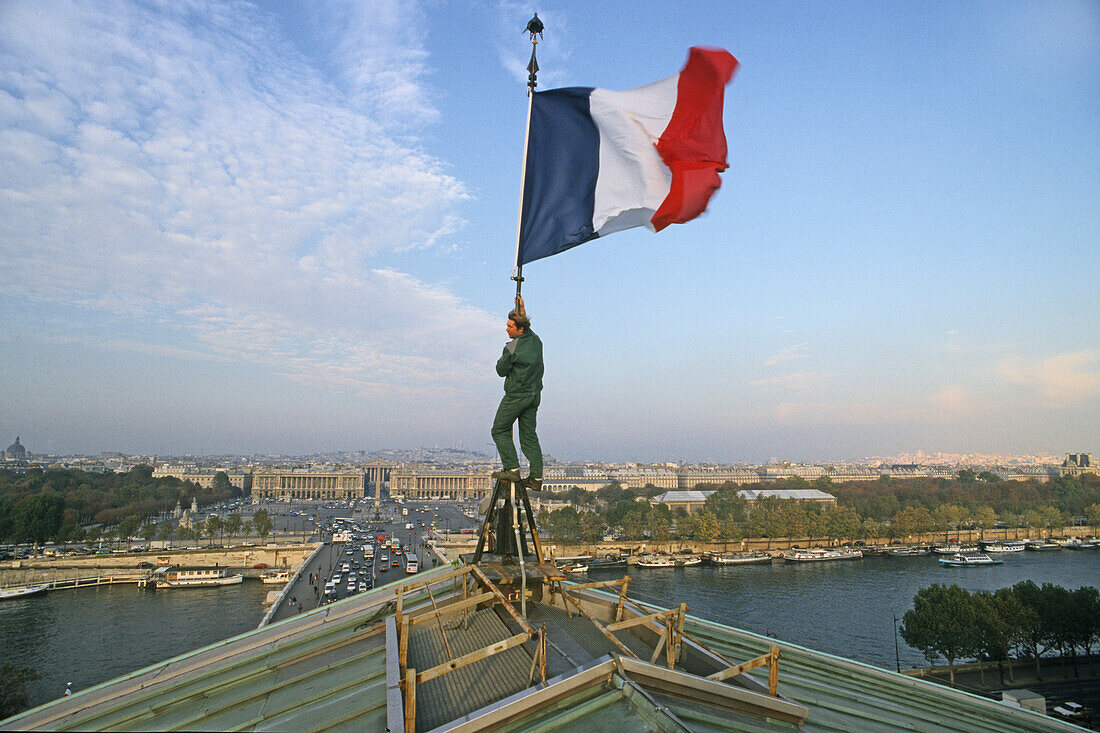 Mann hebt die französische Fahne, Tricolore, Blick zur Madeleine, Place de la Concorde über die Seine, Paris, Frankreich