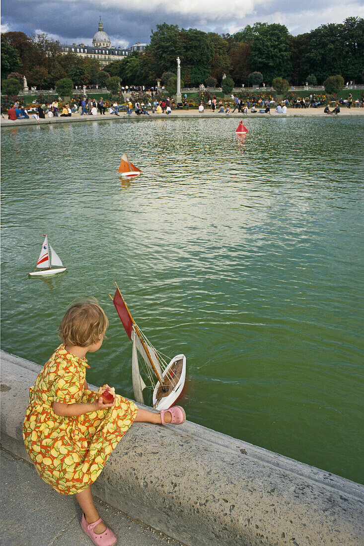 Girl playing with toy sailing boat in a pond, Jardin du Luxembourg, largest public park in Paris, 6e Arrondissement, Paris, France