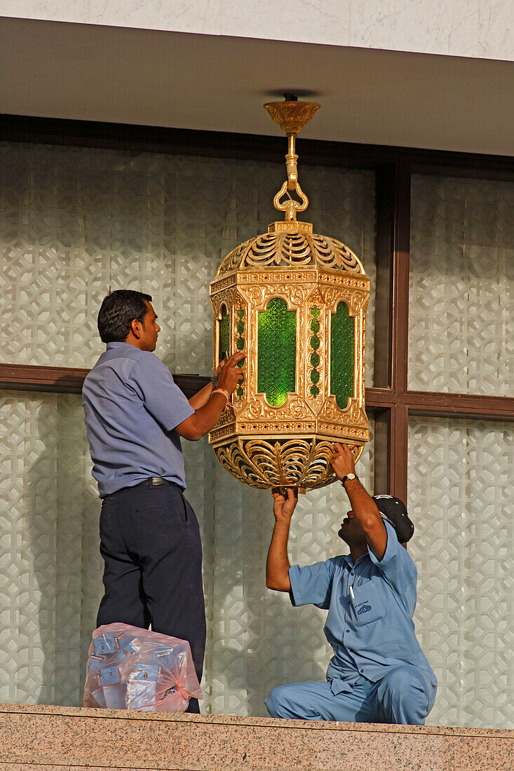 Oman Muskat Sultanspalast Arbeiter reparieren vergoldete Lampe