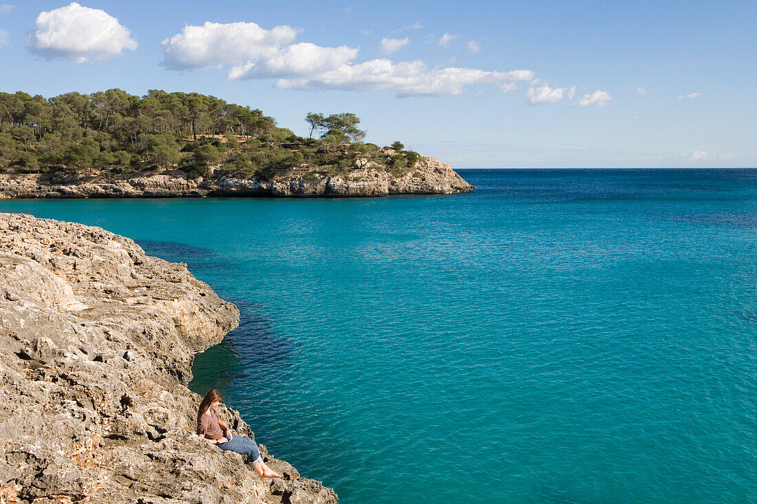 Junge Frau entspannt sich an der Cala Mondrago Bucht, Parc Natural de Mondrago, nahe Portopetro, Mallorca, Balearen, Spanien, Europa