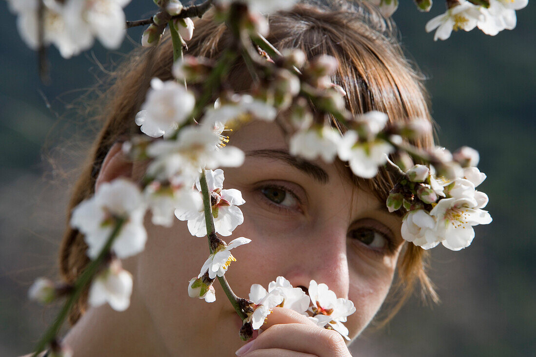Junge Frau bewundert Mandelblüte, nahe Randa, Mallorca, Balearen, Spanien, Europa