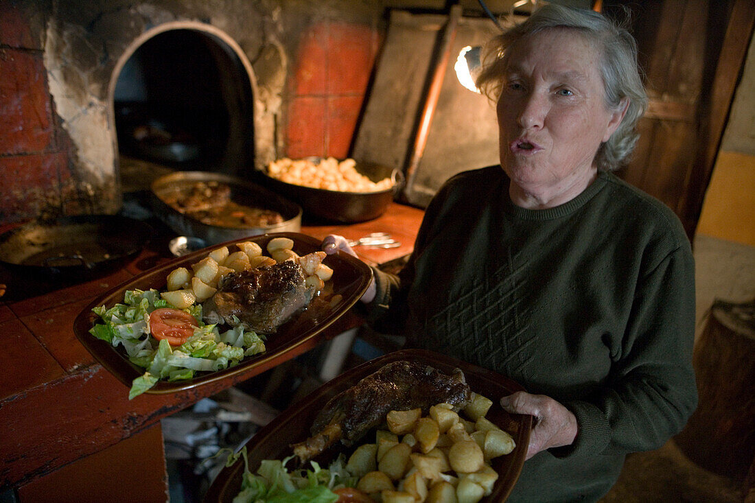 Frau serviert geröstetes Lamm im Es Verger Restaurant nahe Castell d'Alaro, Alaro, Mallorca, Balearen, Spanien, Europa