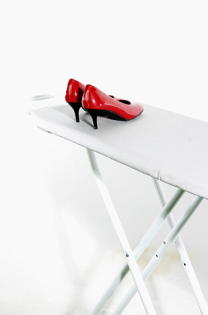 Color, Colour, Concept, Concepts, Fashion, Feminine, Footgear, Footwear, Heels, Housework, Indoor, Indoors, Inside, Interior, Ironing board, Ironing boards, Ironing-board, Object, Objects, Odd, Pair, Pairs, Red, Shoe, Shoes, Still life, Strange, Style, Th