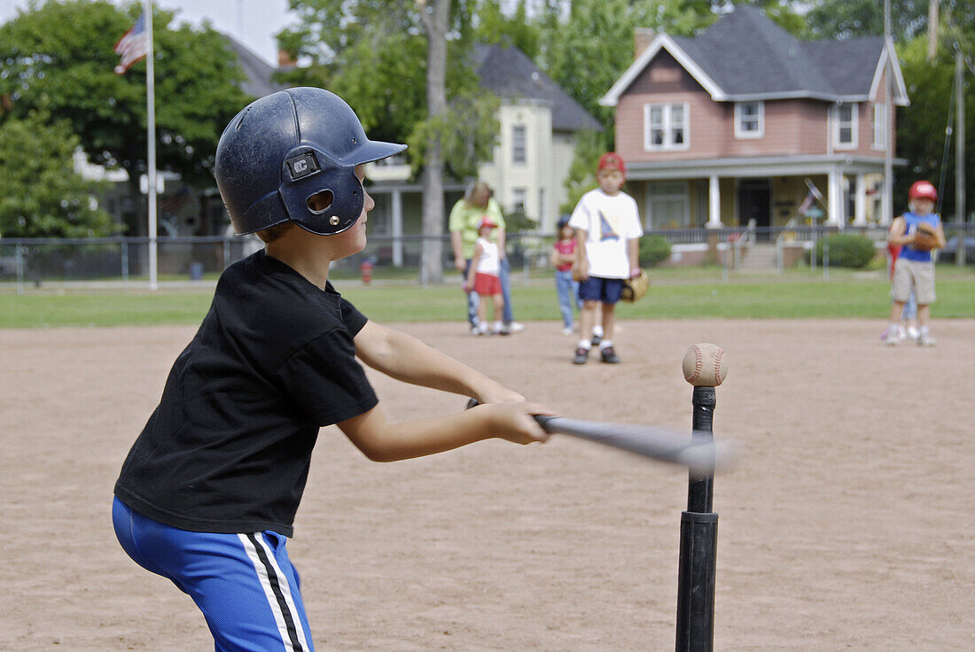 5 to 7 year old Children get their first experience playing baseball from a T.
