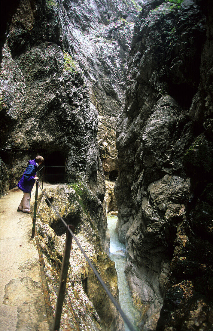 Woman looking in the deep limestone canyon of the Höllentalklamm at Wetterstein mountains, Bavaria, Germany