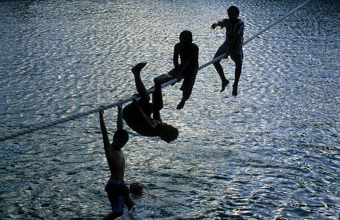 Kinder spielen auf einem Tau im Hafen von Hakahau auf der Insel Ua Pou, Französisch Polynesien