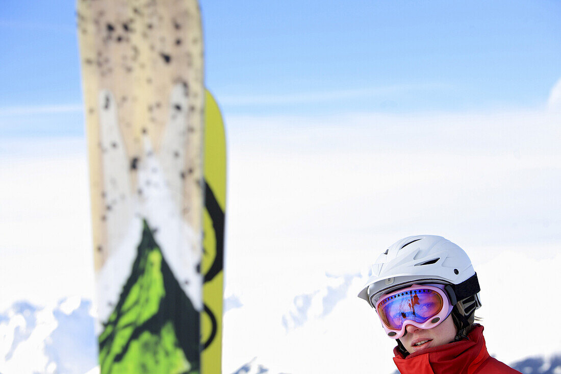 Young woman smiling at camera, snowboards in foreground, See, Ski Region Paznaun, Tyrol, Austria