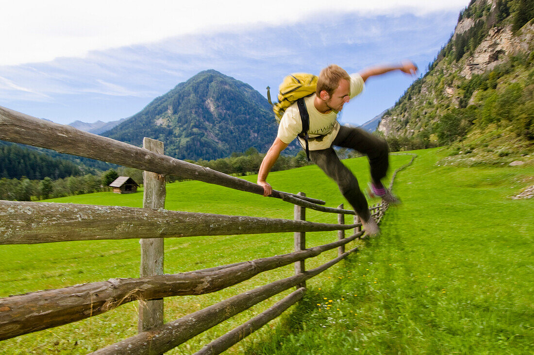 Wanderer springt über Weidezaun, Maltatal, Nationalpark Hohe Tauern, Kärnten, Österreich