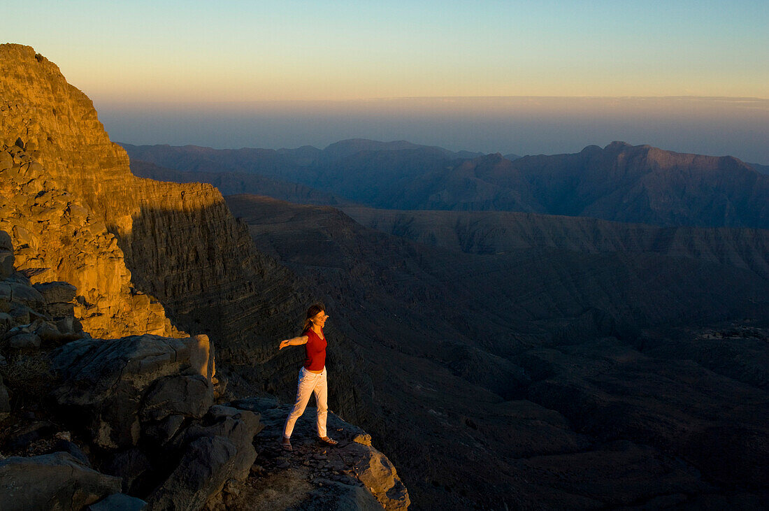 Woman with outstretched arms, feeling the upwind, sunset, Sayh plateau, Mountain landscape, Hajjar mountains, Kashab, Khasab, Musandam, Oman