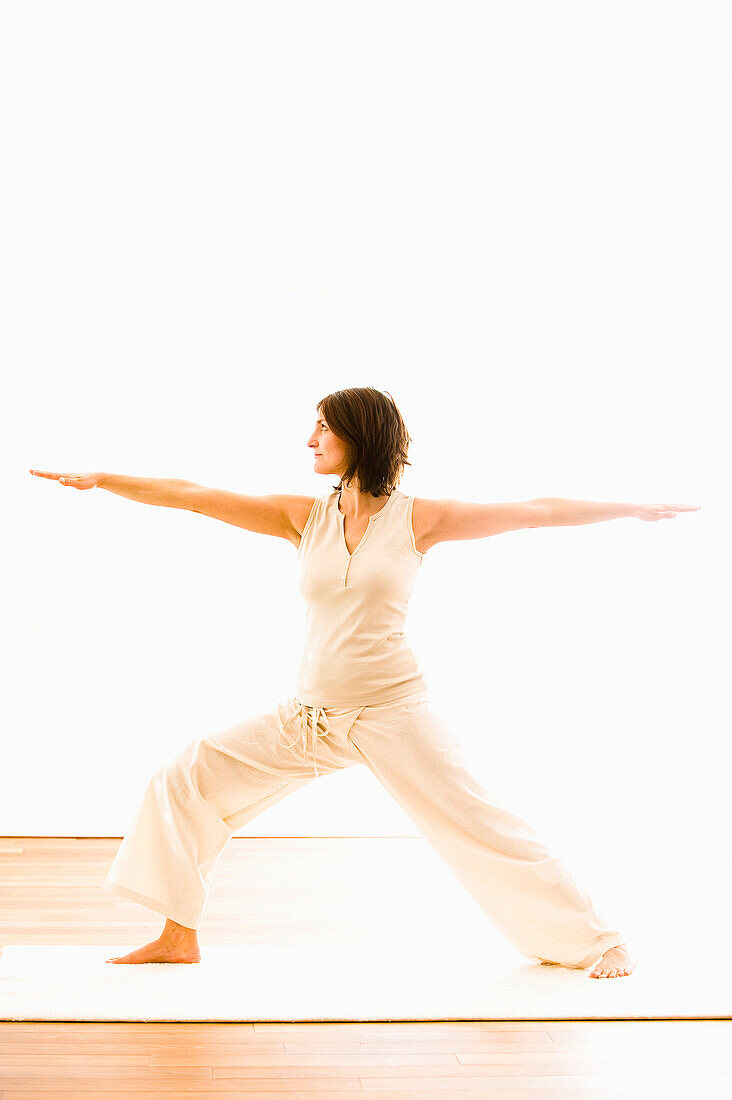 Frau mittleren Alters macht Yoga (Kriegerstellung), Yogastudio in Linz, Österreich
