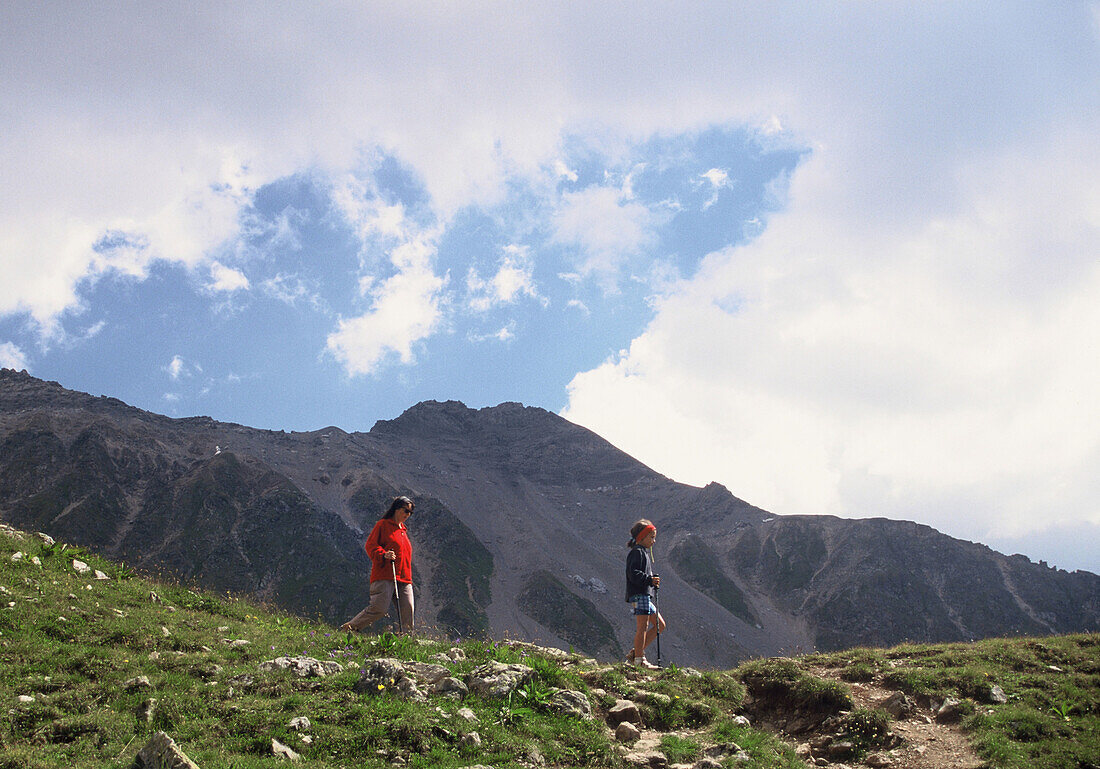 Mother and child hiking in the mountains at Rothorn, over Lenzerheide, Grisons, Switzerland