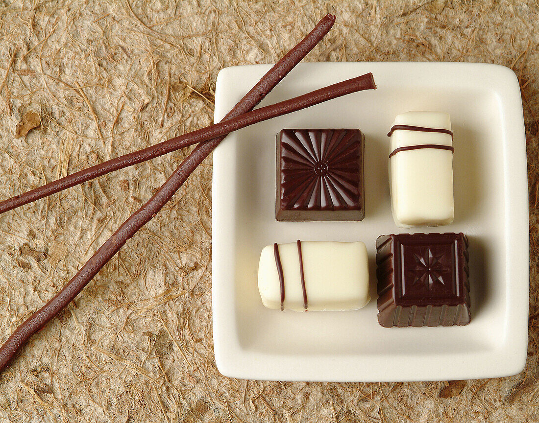 Sushi chocolate with chocolate rolled chopsticks on paper mat