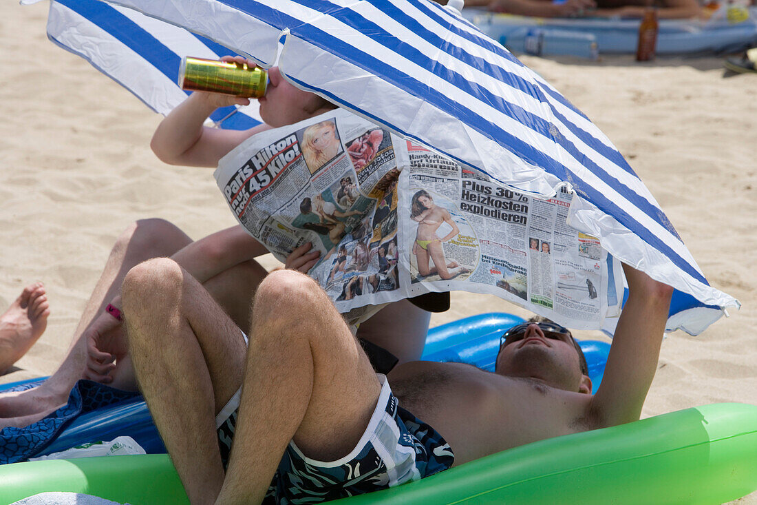 Deutsche Urlauber mit BILD Zeitung am Strand nahe Ballermann, El Arenal, Playa de Palma, Mallorca, Balearen, Spanien, Europa