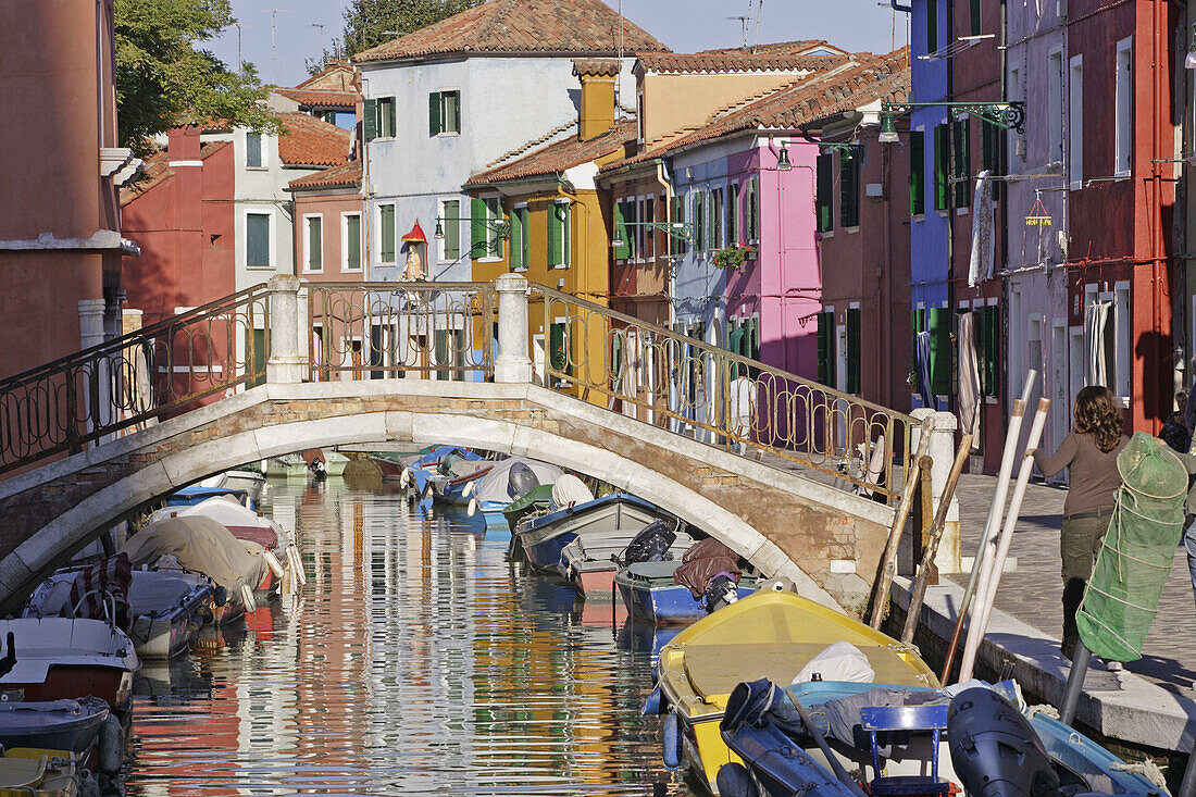 Burano multi-colored houses are reflected in a small canal on the beautiful island in the Venice lagoon. Venice. Veneto. Italy.