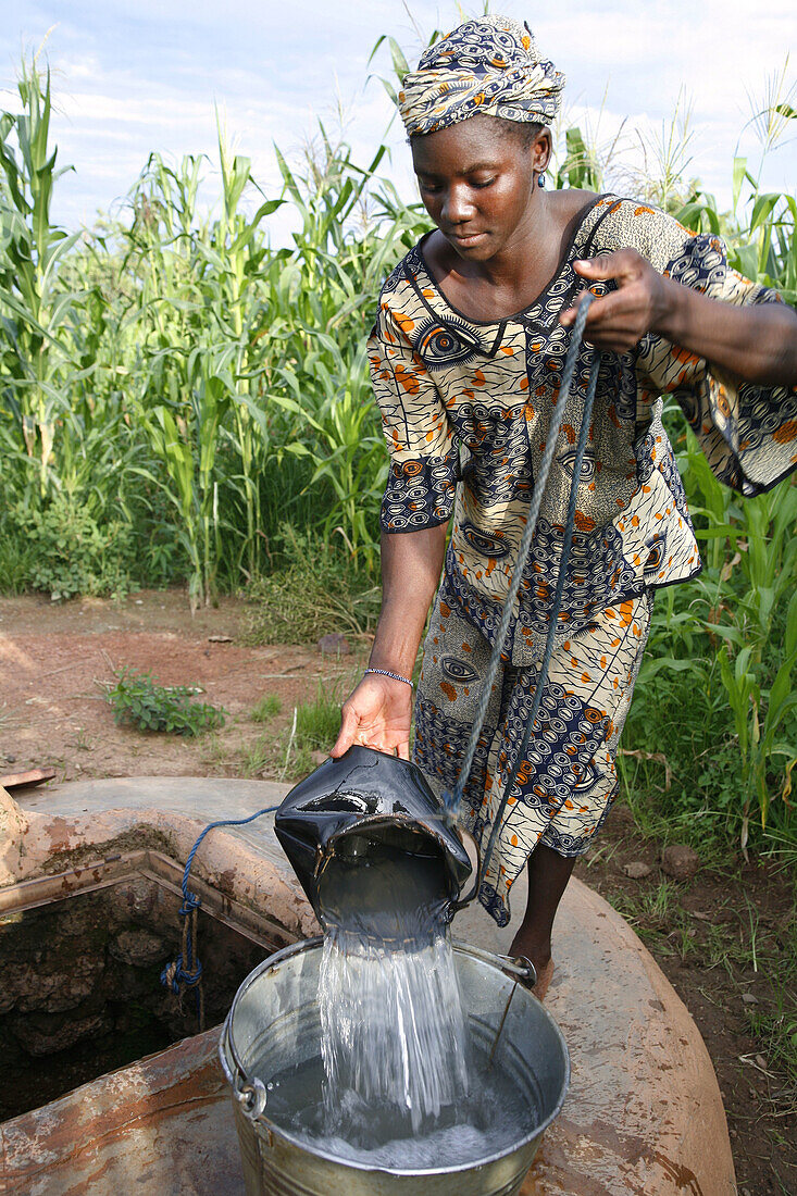 Senoufo young woman getting water from a well. Sikasso region, Mali