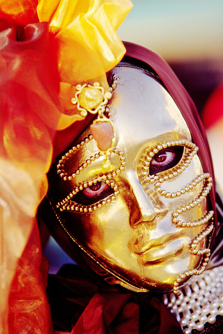 Large clear eyes looking through a gold facemask worn at the yearly carnival in Venice. Italy