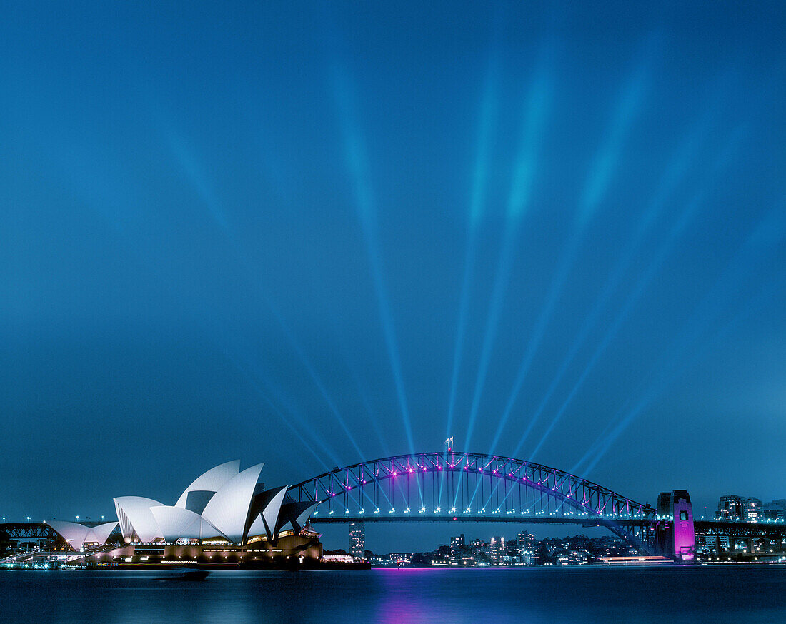 Sydney Opera House and Harbour Bridge at dusk with many spotlights on the bridge lighting upwards.