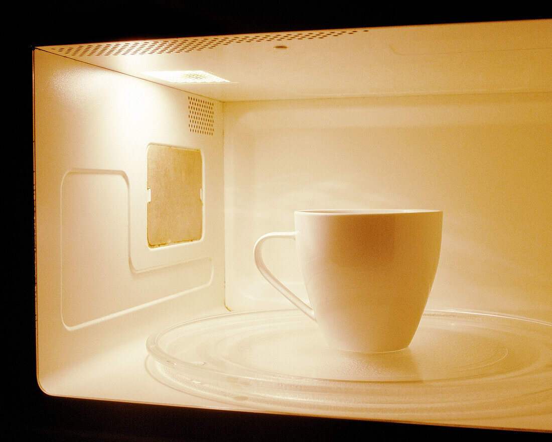 One white coffee mug inside a microwave
