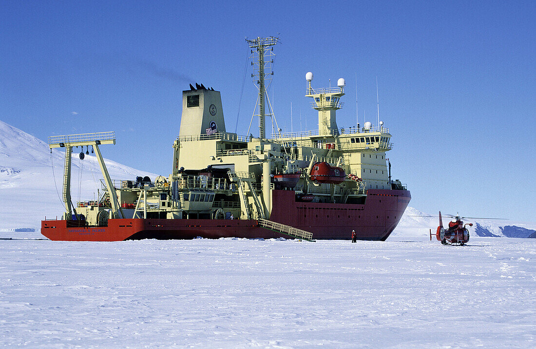 Bow of icebreaker in fast ice in McMurdo Sound with US Coast Guard helicopter nearby, Antarctica