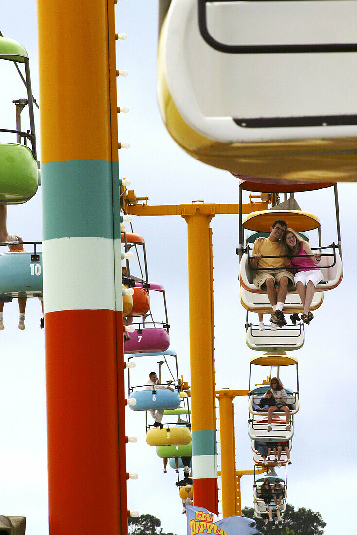 People riding colorful gondola cars above the Santa Cruz Boardwalk in Northern California, USA.