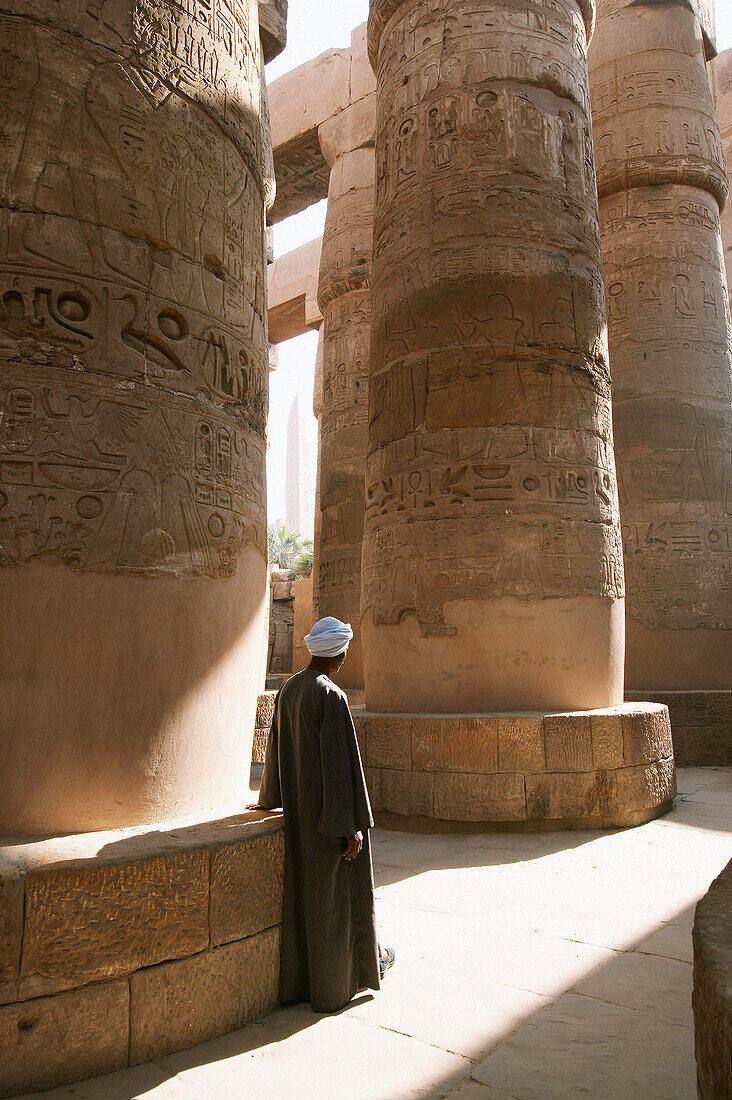 A caretaker at Karnak rests against one of the massive columns. Luxor. Egypt
