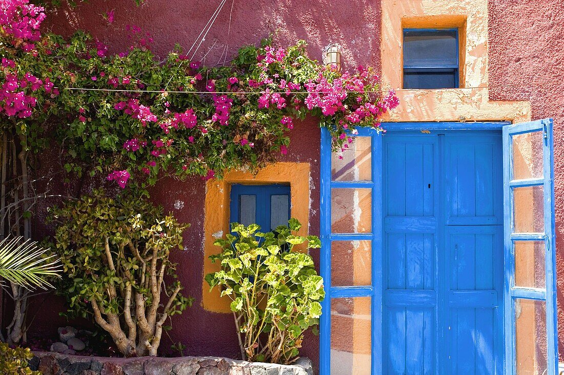 Colourful rustic house with blue door and flowers. Santorini. Greece
