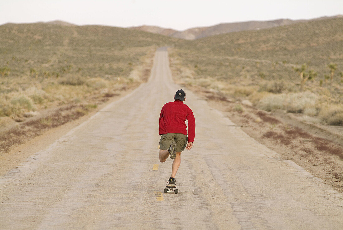 A man skateboarding on a desert road near Lone Pine, California. USA