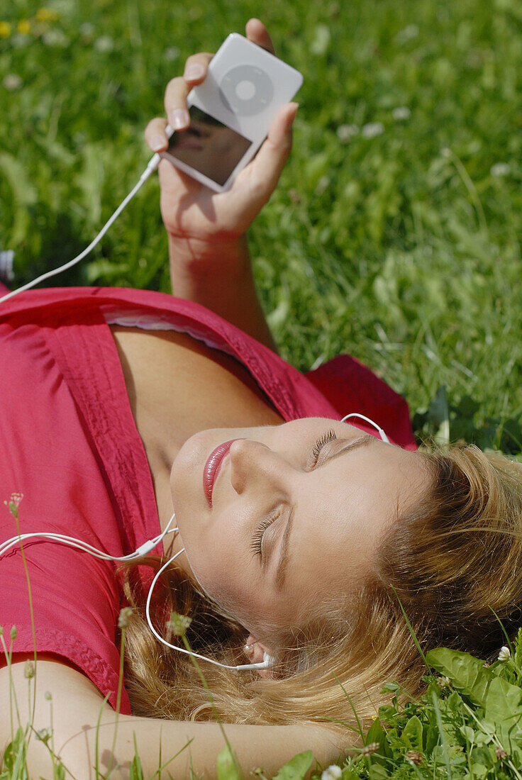 Young girl with a red dress enjoying mp3 music and relaxing