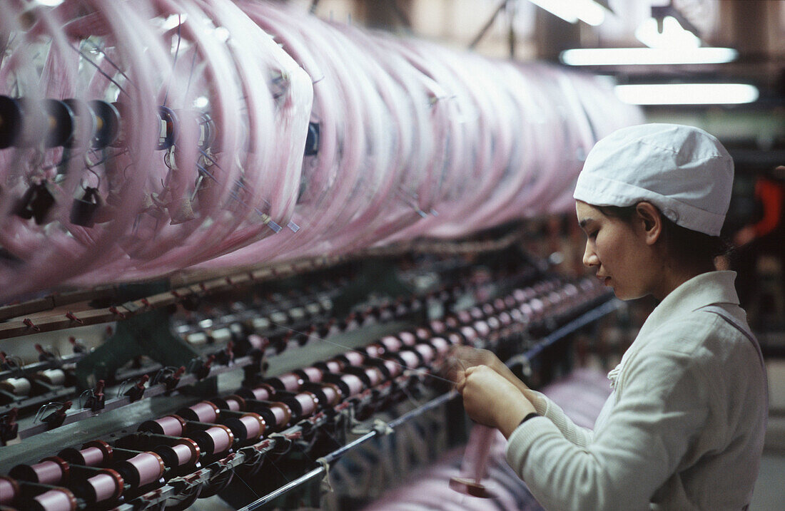 Worker rool up a silk reel. Silk factory. Hotan. Xinjiang Uyghur Autonomous Region. China.
