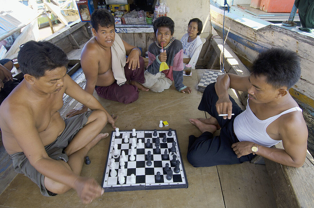 indonesian fishermans playing chess on a boat used as shop. muara angke fish market. jakarta north. indonesia. asia.