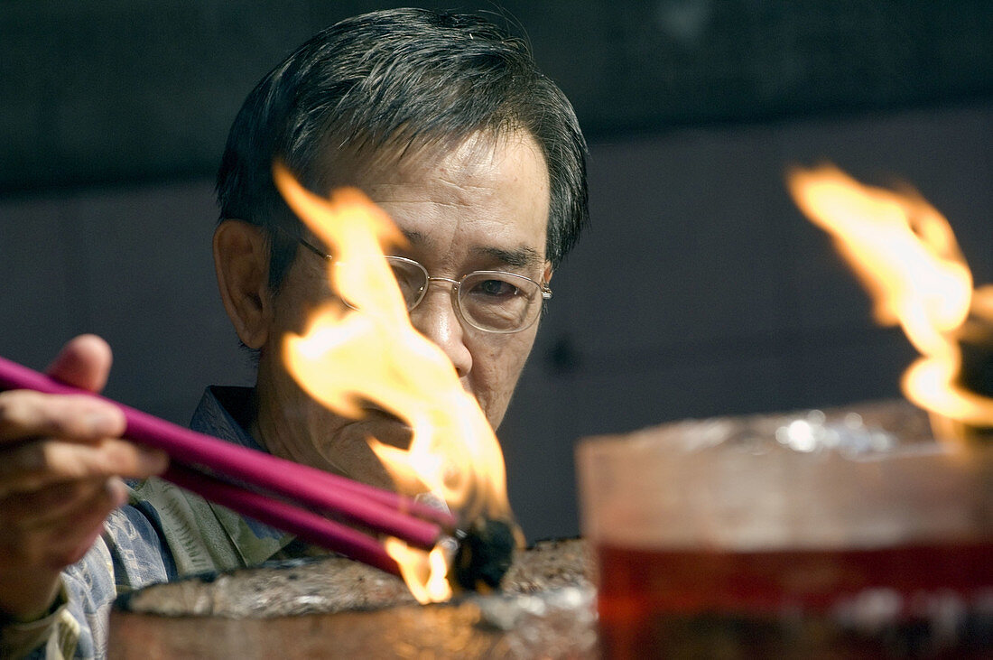 an indonesian man light up incense sticks in Vihara Dharma Bhakti temple in chinatown. west jakarta. indonesia. asia.