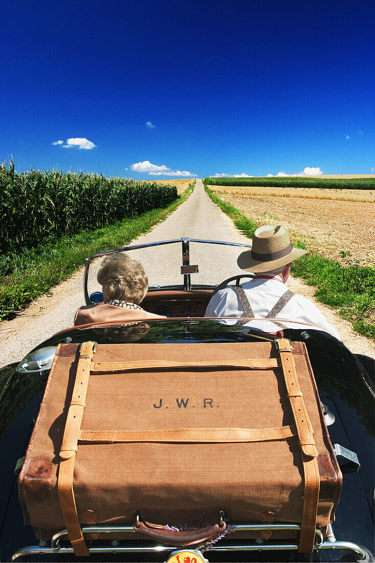 Travelling couple in an open top car (digital composite)