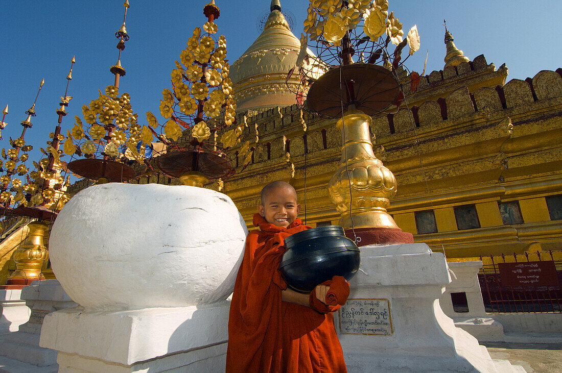 Novice monk holding an alms bowl in fron of the Shwezigon Pagoda, Bagan, Myanmar (Burma)
