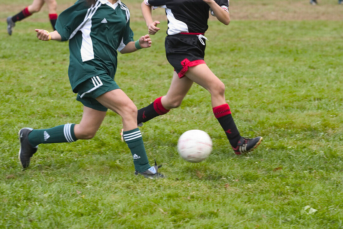 Teen girls, in their uniforms, competing in a soccer game.
