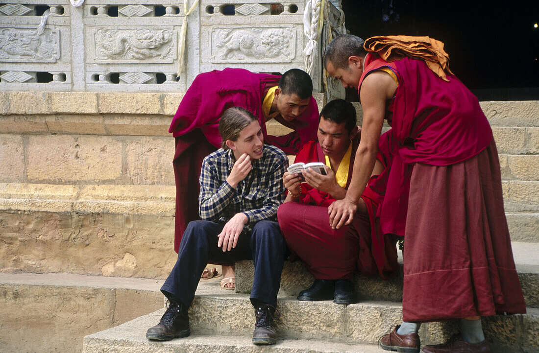 Tourist meeting novice monks at Tibetan-style buddhist (Yellow Hat sect) monastery complex, Songzanlin Si, Zhongdian, Yunnan Province, China