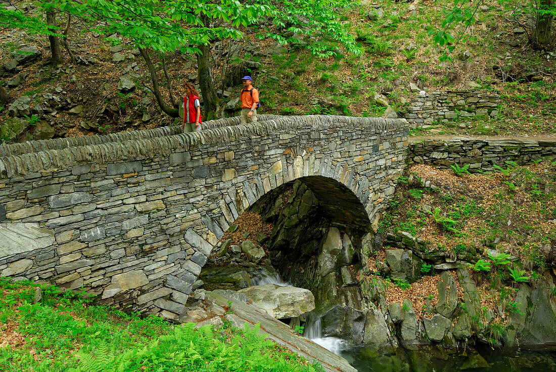 young couple crossing stone bridge, Ticino, Switzerland