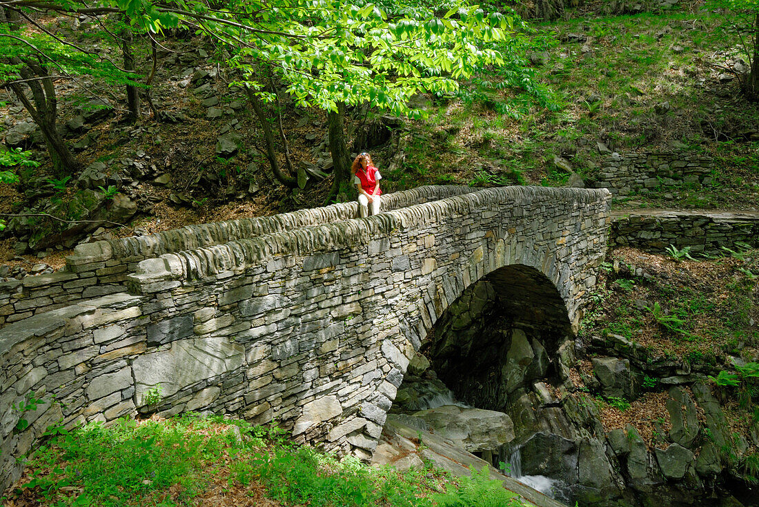 young woman sitting on stone bridge, Ticino, Switzerland